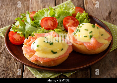 Deliziose uova Benedict con salmone affumicato e salsa olandese e verdure fresche close-up su una piastra orizzontale. Foto Stock