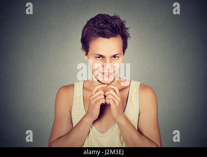 Subdolo intrigante giovane uomo tramando qualcosa isolato sul muro grigio Sfondo. Negativo emozione umana espressione facciale sensazione atteggiamento Foto Stock