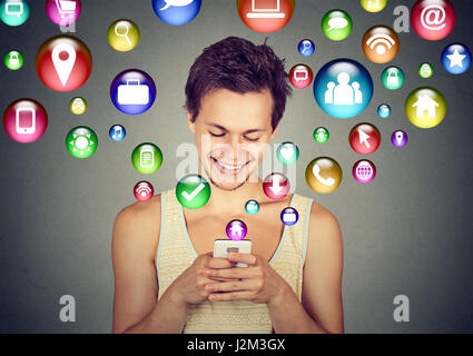 La tecnologia di comunicazione mobile phone high tech concetto. Felice l'uomo utilizzando messaggi di testo sullo smartphone social media le icone delle applicazioni battenti fuori del cellulare Foto Stock