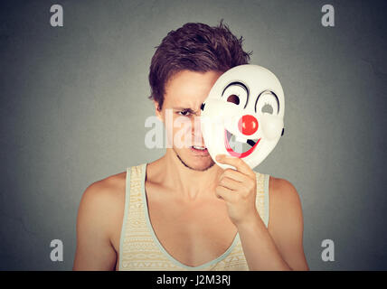 Sconvolto frustrato angry man nascondersi dietro la faccia felice Foto Stock