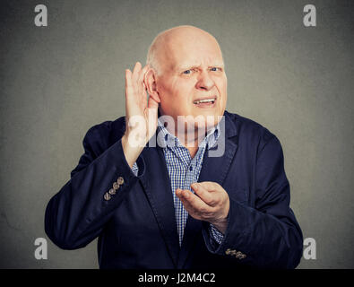 Senior man, con problemi di udito, ponendo la mano sull'orecchio chiedere a qualcuno di parlare Foto Stock
