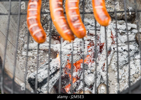 Griglia di cottura con salsicce a un vecchio fire pot con patate al forno Foto Stock