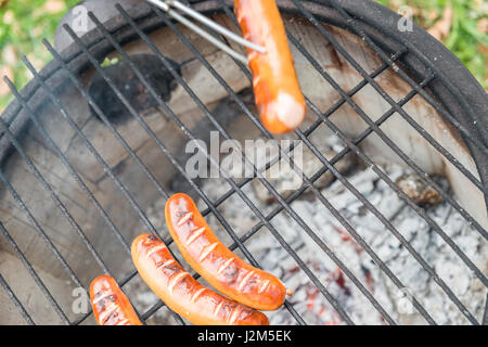 Griglia di cottura con salsicce a un vecchio fire pot con patate al forno Foto Stock