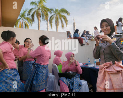 BATAM, Indonesia. Le donne indossano uniformi rosa di parlare mentre gli altri si sono goduti le baracche presso la piazza della città. Foto Stock