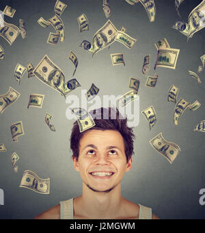 Uomo felice sotto la pioggia di denaro che ricade verso il basso le fatture del dollaro banconote. La libertà finanziaria nozione Foto Stock