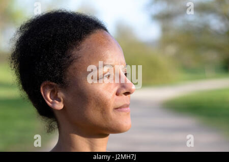 Vista laterale di una giovane donna africana mentre lei sta cercando la distanza Foto Stock