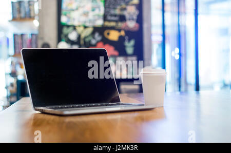 Selezionare la messa a fuoco su blank screen monitor portatile su tavola di legno in cafe per advrtising Foto Stock