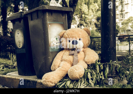 Il teddy-bear è stato buttare via seduta byside i rifiuti nel cestino Foto Stock