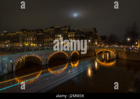 Sentieri di luce dal passaggio di un battello sui canali di Amsterdam, Paesi Bassi, presa in corrispondenza dell'intersezione di keizersgracht e reguliersgracht Foto Stock