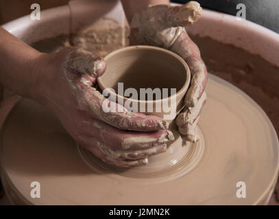 Potter fa una pentola di creta, lavorando sul tornio del vasaio. Foto Stock