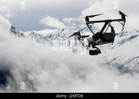 Drone quad copter con alta risoluzione Telecamera digitale volando sopra la montagna innevata Foto Stock