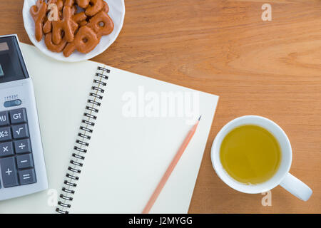 Matita e calcolatrice su bianco blank notebook, alfabeto i cookie su piastra bianca, miele tè in tazza bianca, il tutto su un tavolo di legno, sala per il testo Foto Stock