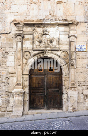 In legno porte doppie e gesuita stemma sul vecchio Colegio de los Jesuitas, un edificio storico nella vecchia città medievale di Cuenca, Spagna Foto Stock