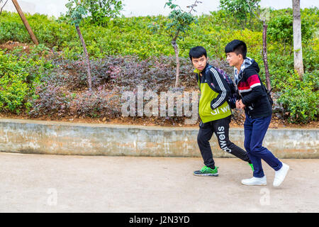 Kaili, Guizhou, Cina. Due ragazzi adolescenti camminando sul marciapiede. Foto Stock