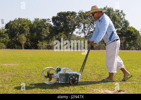 Chiang Mai, Thailandia - 28 dicembre 2016 - Lavoratore spinge il rullo di vernice per dipingere la linea bianca sul campo di calcio in un campo di calcio in Chiang Mai Thailandia su Foto Stock