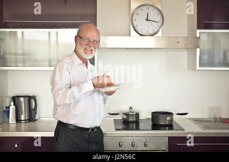 Il vecchio uomo di mangiare in cucina Foto Stock