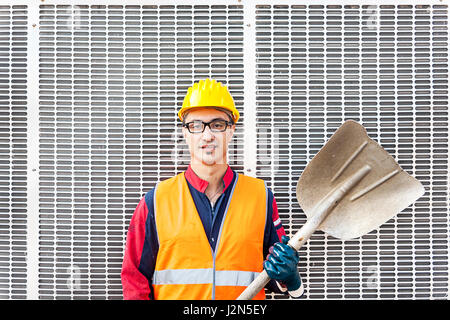 Ritratto di un giovane ingegnere che indossa un casco contro lo sfondo di metallo Foto Stock