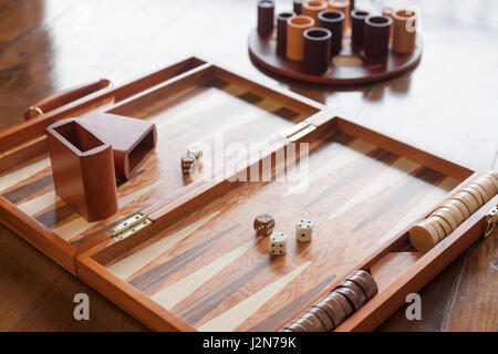 Backgammon in legno gioco impostato su pavimento di legno, fuoco selettivo sui due dadi bianco Foto Stock