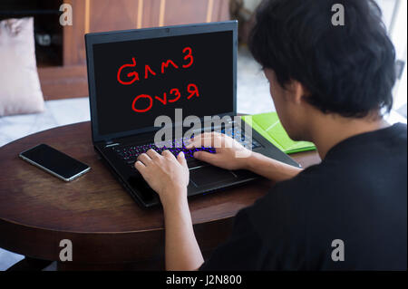 Immagine di offuscata indietro vista di testa di concentrato di Asian Gamer giocando a casa Foto Stock