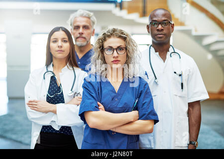 Un gruppo di fiducia dei medici con le braccia incrociate in piedi in un ospedale e guardando la fotocamera. Foto Stock