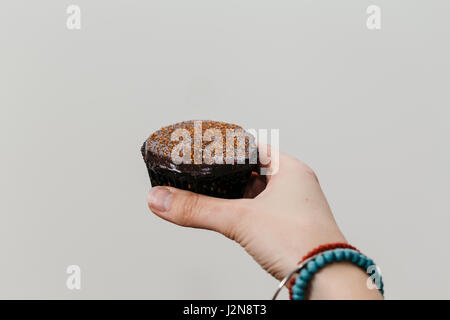 Close-up di donna di mani di cioccolato tortini di Halloween con decorazioni di colore arancione Foto Stock