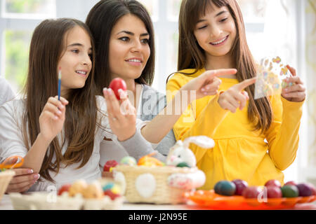 Giovane madre sorridente con due figlie di pittura delle uova di Pasqua Foto Stock