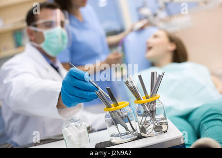 Chiusura del dentista tenendo strumento dentale dal recipiente in clinica Foto Stock