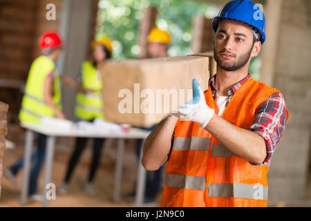 Giovane lavoratore portare la trave di costruzione al lavoro Foto Stock