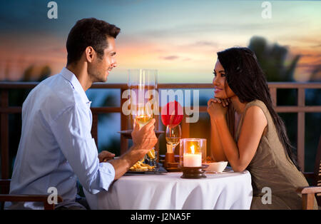 Coppia felice sulla serata estiva avente una romantica cena all'aperto Foto Stock