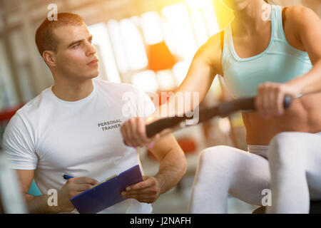 Giovane maschio formatore dando istruzioni ad una donna in una palestra Foto Stock