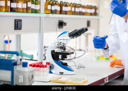 Scienziato chimico preparare luogo campione di liquido sul vetrino del microscopio Foto Stock