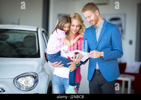 Rivenditore di auto che mostra la brochure giovane donna con bambino alla concessionaria auto berlina Foto Stock