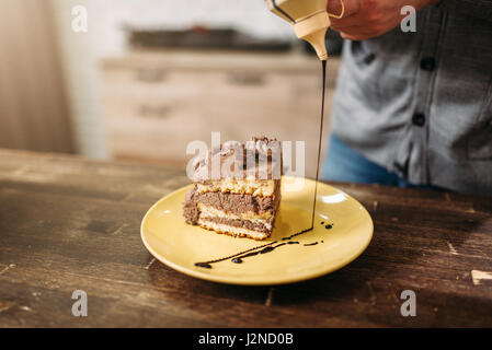 Pezzo di torta sulla piastra, decorazione con salsa al cioccolato. Dessert fatti in casa, capolavoro culinario Foto Stock