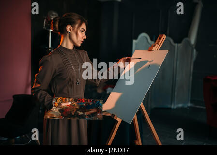 Pittore femmina con pennello e tavolozza in mani in arte studio. Pittura a olio, il pennello disegno Foto Stock