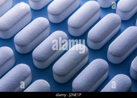 Alcune pillole allineati isolato su sfondo blu Foto Stock