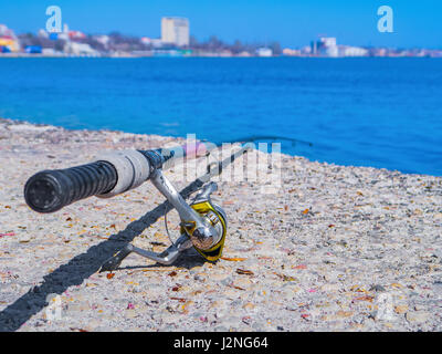 Canna da pesca si trova in riva all'oceano Foto Stock