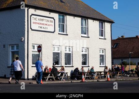 Herne Bay, Kent, Regno Unito. Il 29 aprile, 2017. Regno Unito notizie meteo. Un soleggiato la sera del primo giorno del Mayday Bank Holiday weekend consente alle persone di andare in spiaggia anche se rimangono avvolti fino contro il freddo e sedersi fuori l'hotel Hampton Inn a waterside pub. Credito: Richard Donovan/Live Alamy News Foto Stock