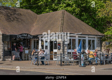 La gente seduta al di fuori del Vecchio Mulino sala da tè e caffè, godendo di spuntini e gelati a Christchurch Quay, Dorset, Regno Unito Foto Stock