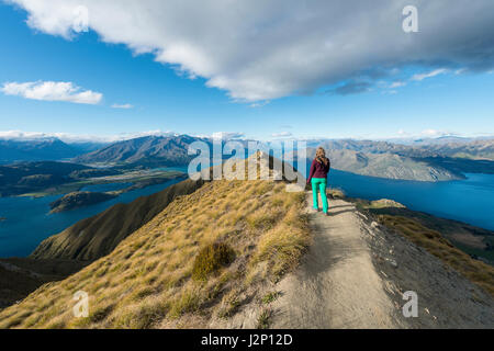 Donna escursionismo sul crinale, vista sulle montagne e sul lago, Roys picco, il lago Wanaka, Alpi del Sud, regione di Otago e Southland, Nuova Zelanda Foto Stock