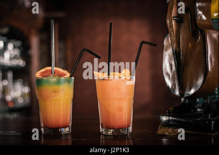 Due vibrante di frutta e cocktail alcolico con paglia al tavolo bar Foto Stock