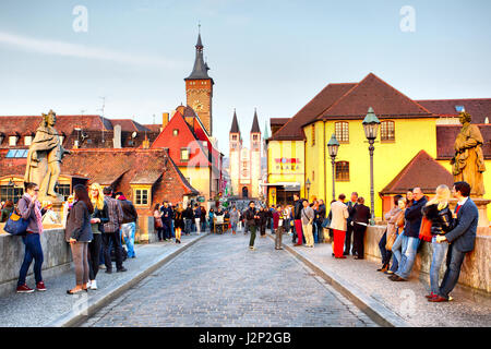 Wurzburg, Germania - 21 Aprile 2013: la gente a piedi sul vecchio ponte principale oltre il fiume principale nella Città Vecchia di Wurzburg di sera Foto Stock