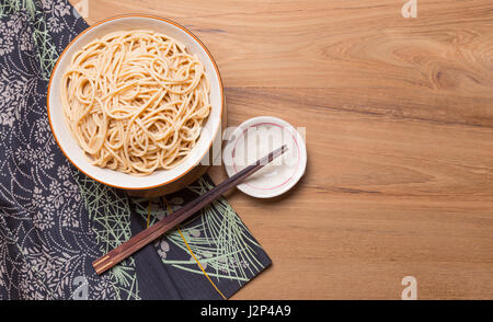 Ciotola di tagliatelle con bacchette di legno di stile Giapponese tabella panno sul tavolo di legno, sala per copyspace Foto Stock