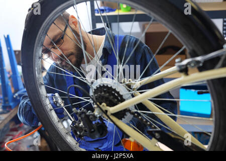 Il pompaggio della ruota di bicicletta. Pompaggio del moto. Il meccanico in bike service pompata la ruota di bicicletta con un compressore aria. Foto Stock