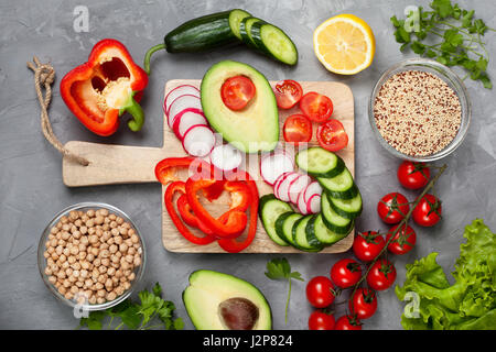 Ingredienti per una ciotola buddha: la quinoa, ceci, verdure fresche sul cemento grigio Sfondo. Vista da sopra Foto Stock