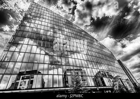 Immagine monocromatica del triangolo edificio con edifici riflettendo sulla parte anteriore in vetro Foto Stock