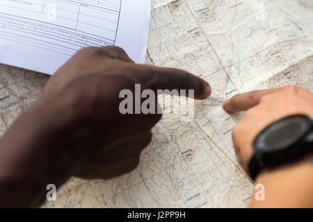 Due escursionisti punto in una mappa, mentre la navigazione del loro prossimo itinerario, mentre passeggiate in zone rurali della Tanzania. Foto Stock