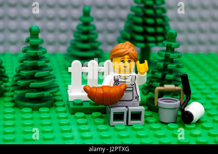 Tambov, Federazione Russa - 21 settembre 2016 Lego pittore è in appoggio e di mangiare croissant nel parco. Studio shot. Foto Stock