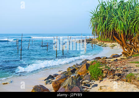Il vecchio bastoncini di pesca sulla riva della spiaggia di Ahangama attende i pescatori, di venire qui ogni giorno, Sri Lanka. Foto Stock