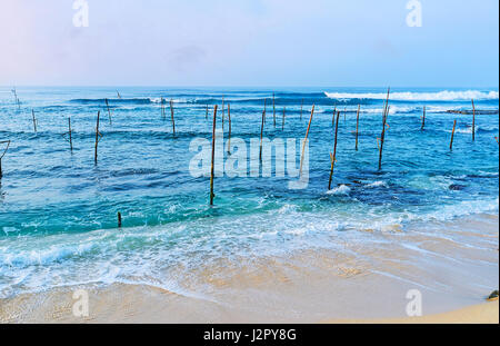 I bastoncini di pesca attendere per i loro proprietari, i pescatori locali, di venire qui ogni mattina, ahangama, sri lanka. Foto Stock