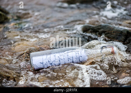 Lavata dal mare vecchia bottiglia con un messaggio. Foto Stock